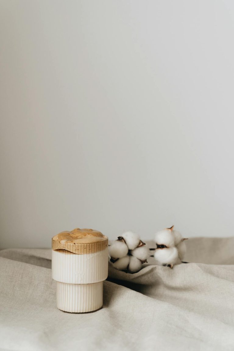 Elegant vertical shot of dalgona coffee in glass with cotton decoration, showcasing modern minimalist design.